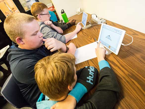 Three students work on iPads in the Outreach Lab