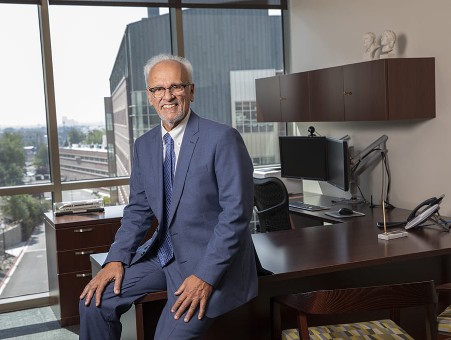 man wearing suit in his office with large window behind him