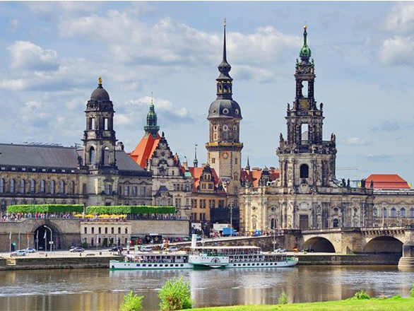 A row of historic buildings on the shore of a river.