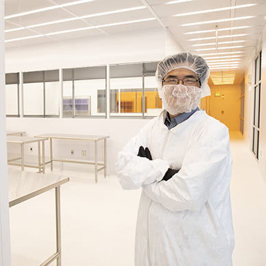 professor in lab suit inside a cleanroom