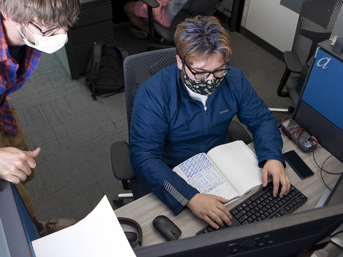 student works at graduate workstation with notebook open