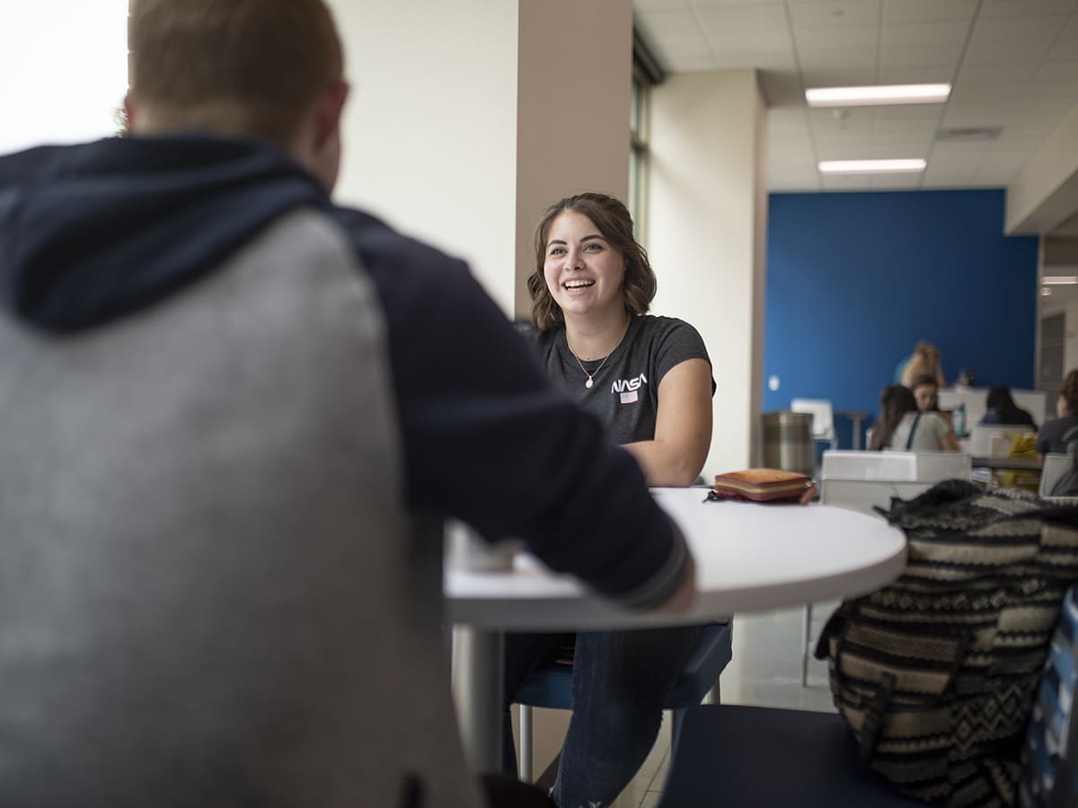 Two students talk at a table