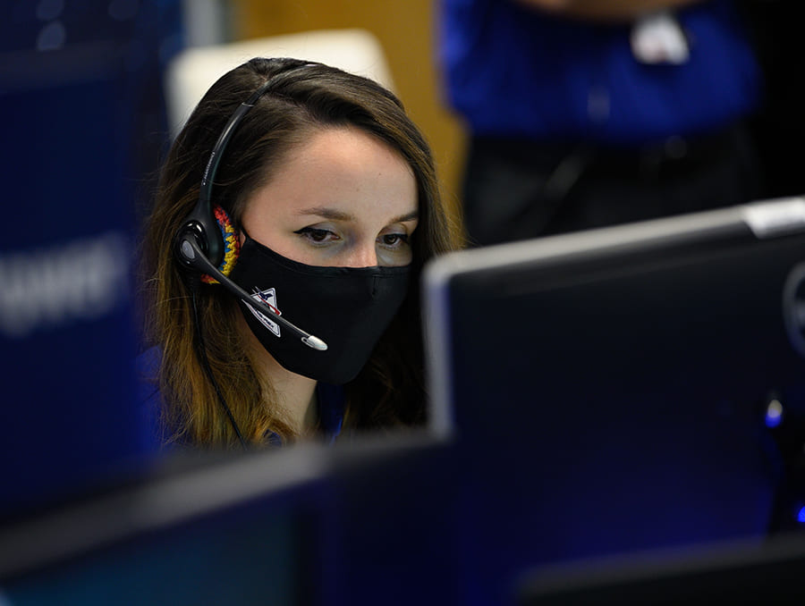 Sierra Gonzales wearing headphone and mic behind computer in command station