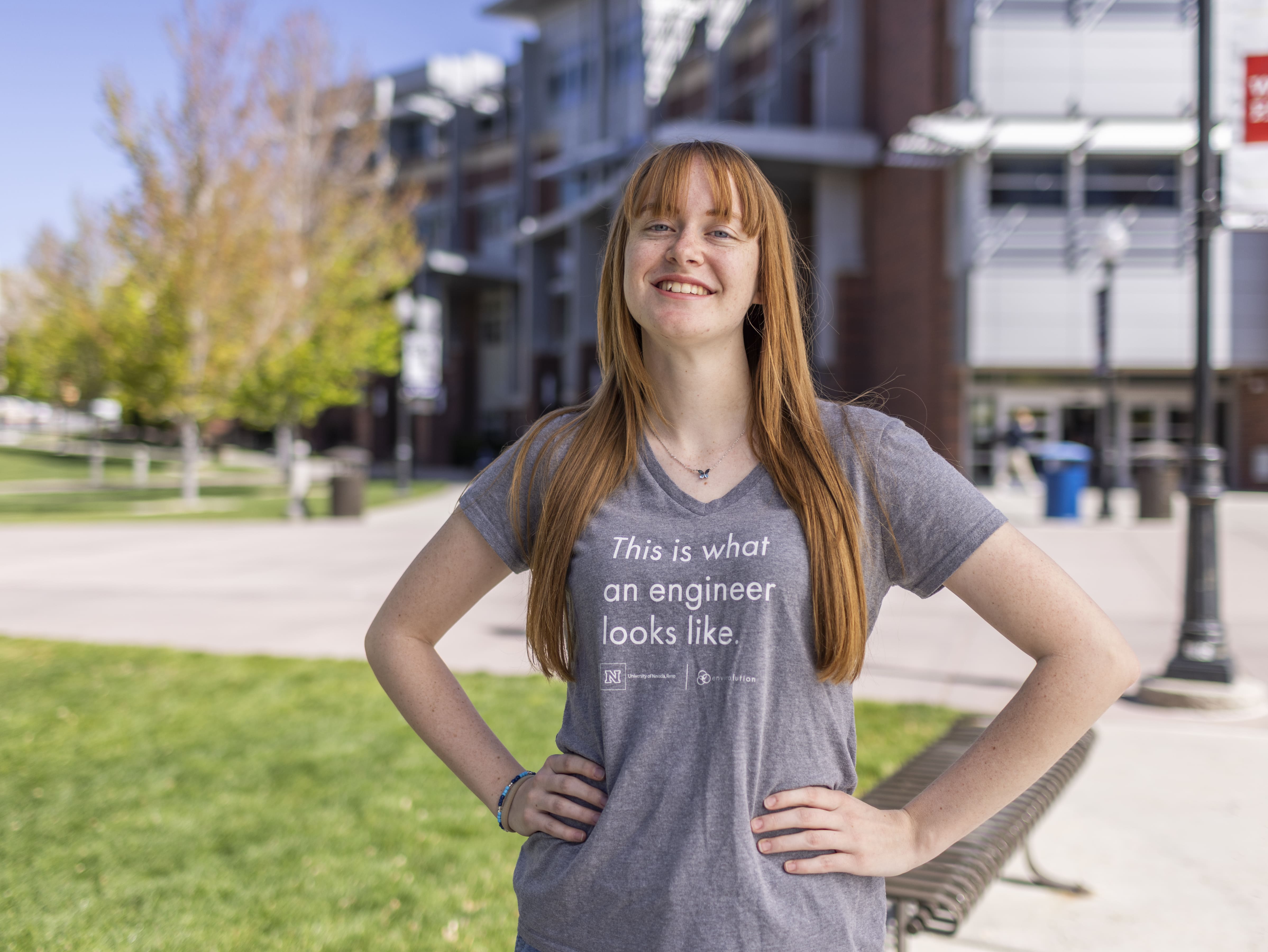 Woman wearing a T-shirt with the words "This is what an engineering looks like," stands in front of a building.