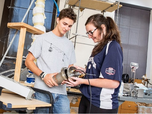 Two people in a lab holding a canister.