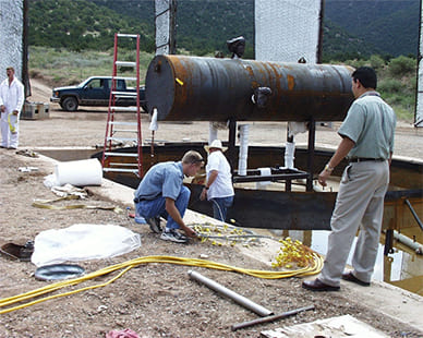 Person working on test site next to large pit and metal structure