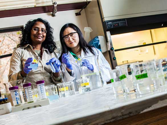 Twos students in lab coats with beakers