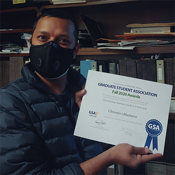 Student Chiranjivi Bhattarai, wearing a face covering, holds up a paper certificate. 