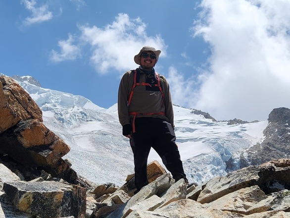 Ludving standing by a high mountain.