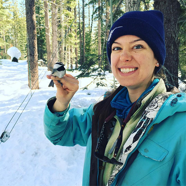 Photo of Lauren Benedict with a wild chickadee.