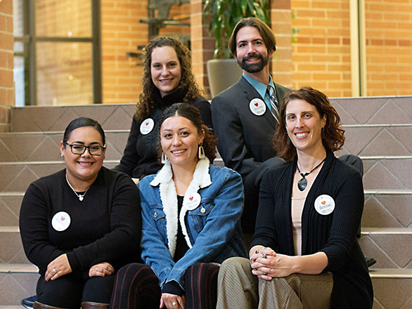 Five members of a GSA-recognized student club sit on building steps.