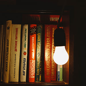 Dark books illuminated by a hanging lightbulb
