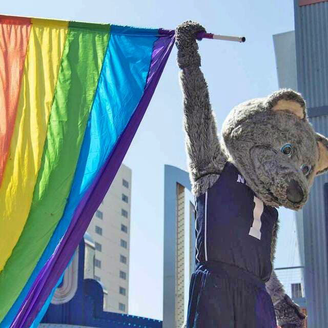 Mascot Alphie holding a pride flag