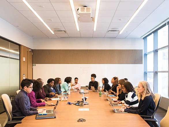 A group of people sit talking in a company boardroom.