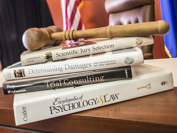 A stack of books on a table all relate to psychology in law and jury selection.