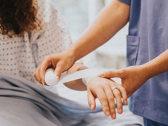 A medical professional wraps a bandage around the arm of a patient. 