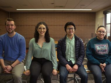 Four students sit on a table in the Reynolds School