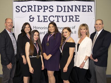 Students and the Scripps family pose in front of a backdrop.