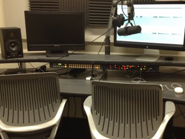 Two chairs, a microphone and a computer in a room.