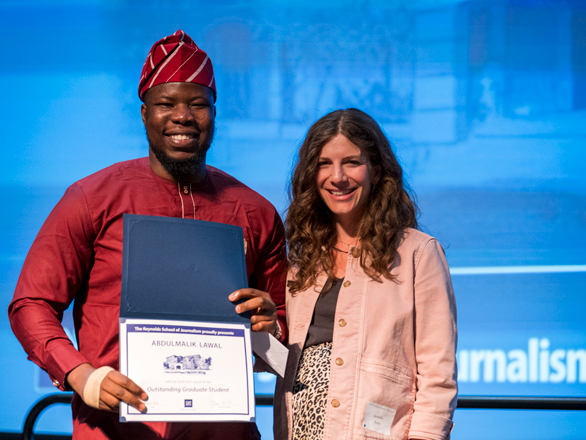 A graduate student receiving an award on stage alongside a faculty member.