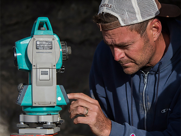 Anthropology professor looks at piece of equipment outside
