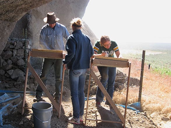 Archaeology dig participants sift dirt looking for artifacts