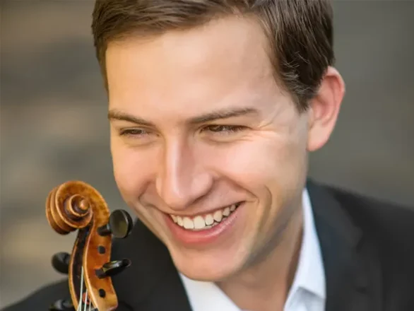 James Thompson wears a suit and poses with his violin.