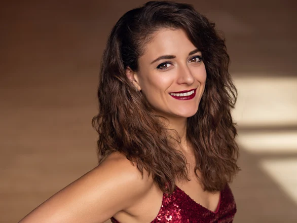 Milena Pajaro-van de Stadt wears a red dress and smiles for a publicity photo.