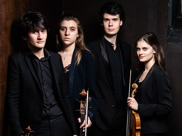 The four members of Le Consort wear black suits and pose for a publicity photo.
