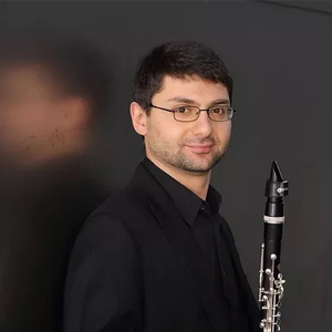 Boris Allakhverdyan poses for a headshot while holding a clarinet.