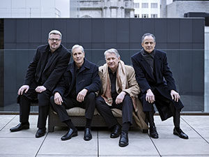 Four members of the Emerson Quartet sit and pose for picture outside
