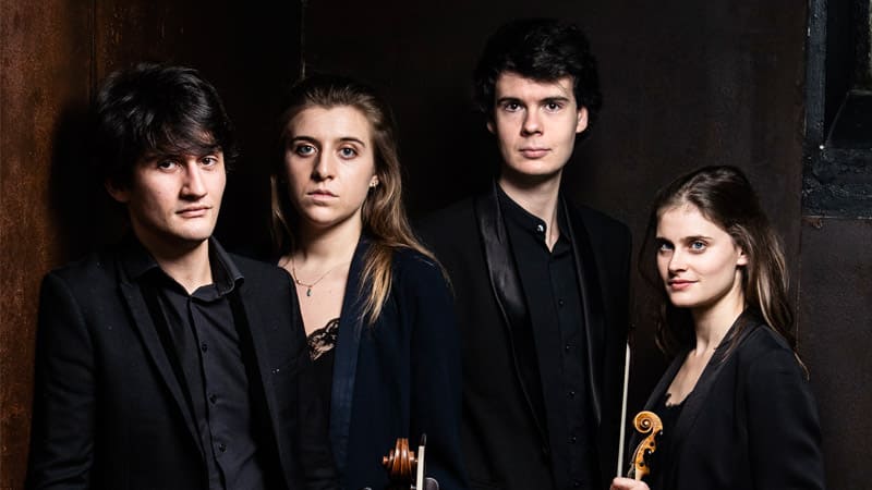 The four members of Le Consort wear black suits and pose for a publicity photo.