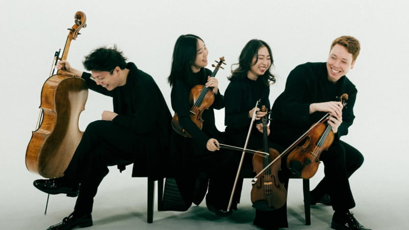 four musicians holding instruments and smiling