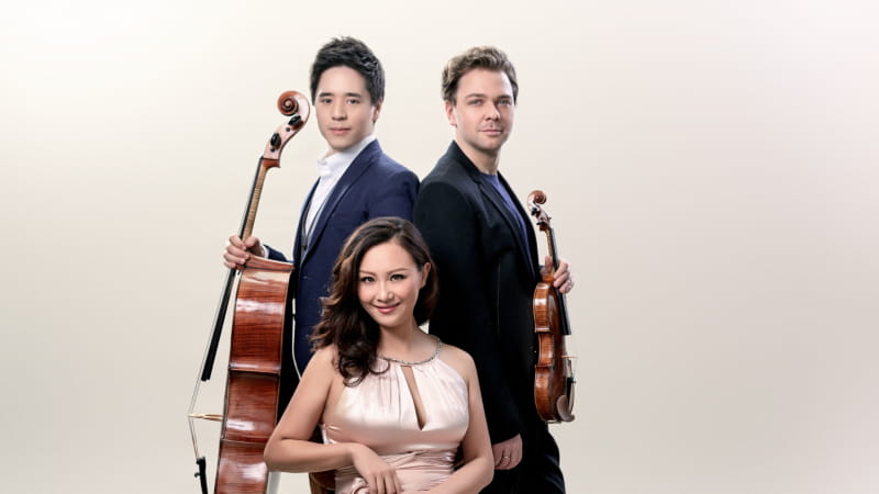 three musicians standing together holding instruments