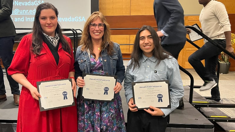 three people holding awards smiling at camera