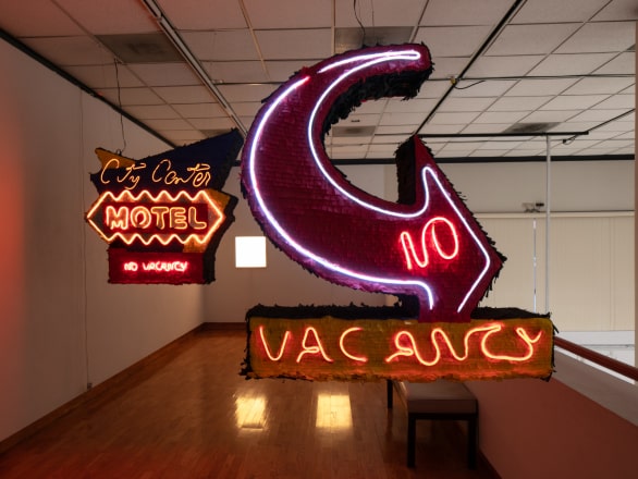 neon sign saying "city center motel no vacancy" with arrow pointing to the right