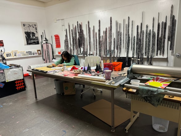 student in art studio working on art with art hung on walls