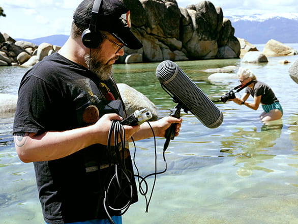 man with boom mic standing in water at Lake Tahoe