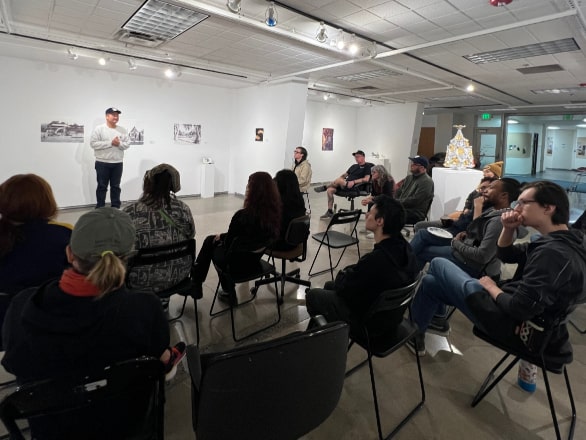 people sitting in chairs watching an art presentation