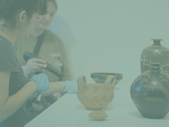 Museum worker overlooks student learning how to take care of sculptures