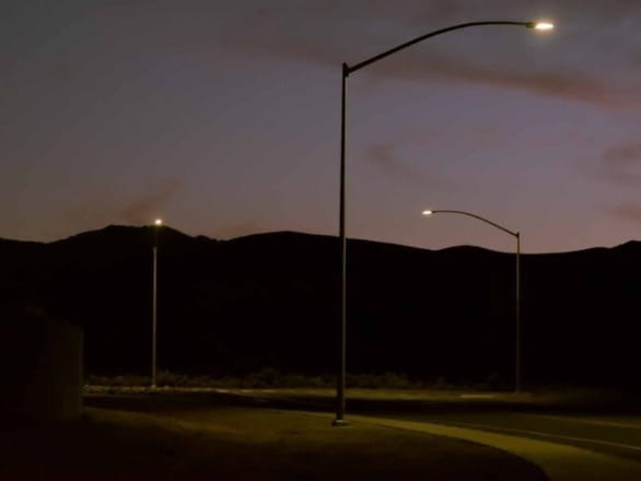 photograph of street lights lit up at dusk with mountains in background