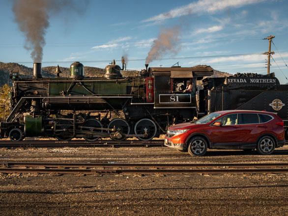 Newman in a train next to a SUV