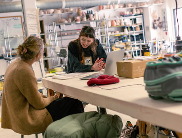 two women sitting at computer in art studio