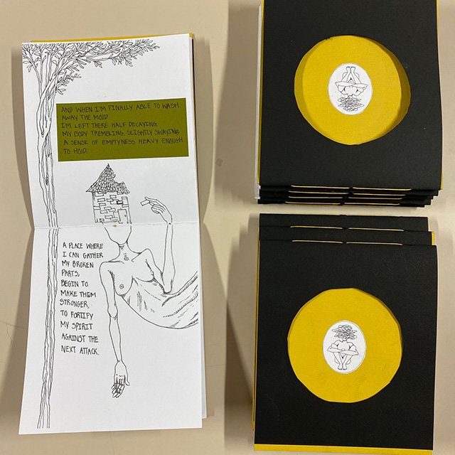 Black and yellow book close on table next to open page about humans being broken