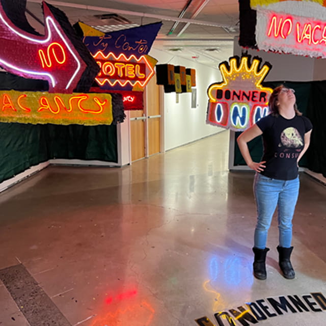 girl standing in art exhibit looking up with hands on hips