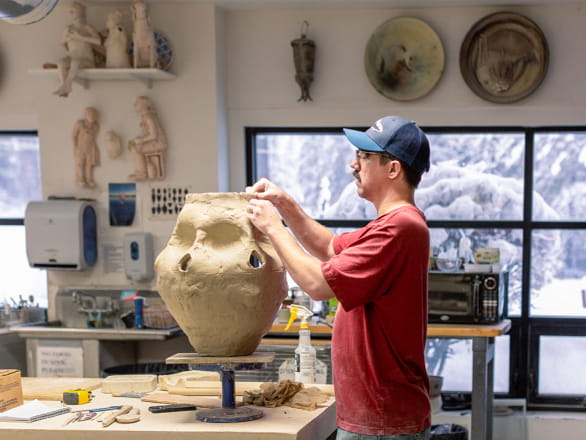 man working on sculpture in art gallery