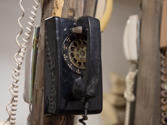 old black dial telephone on wooden post