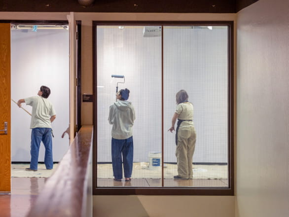 three people painting art gallery walls