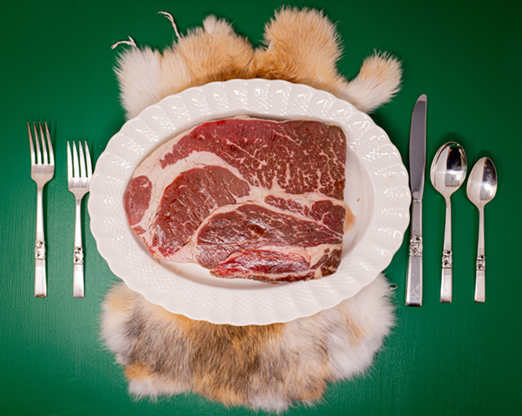 steak on white plate with utensils next to it and green background