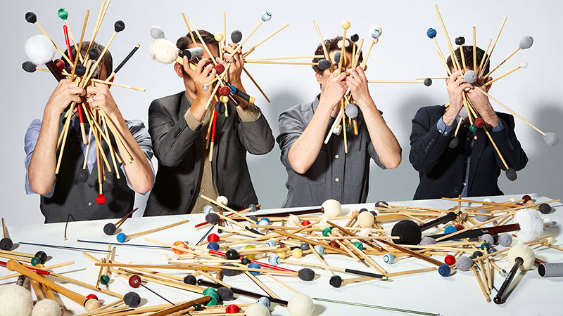 Students with instrument mallets held up in handfuls covering their faces